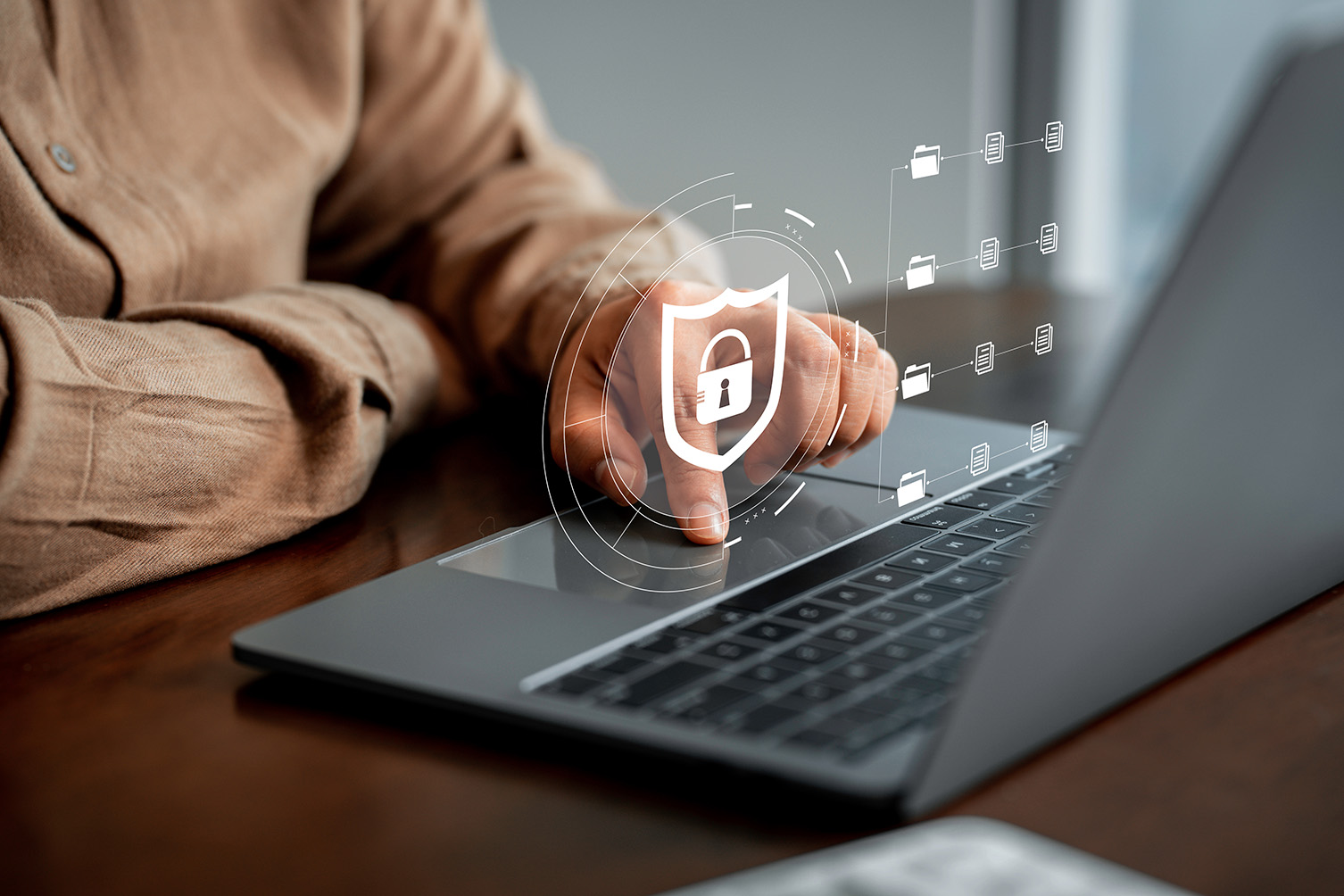 Person using a laptop beneath illustrated security and file icons