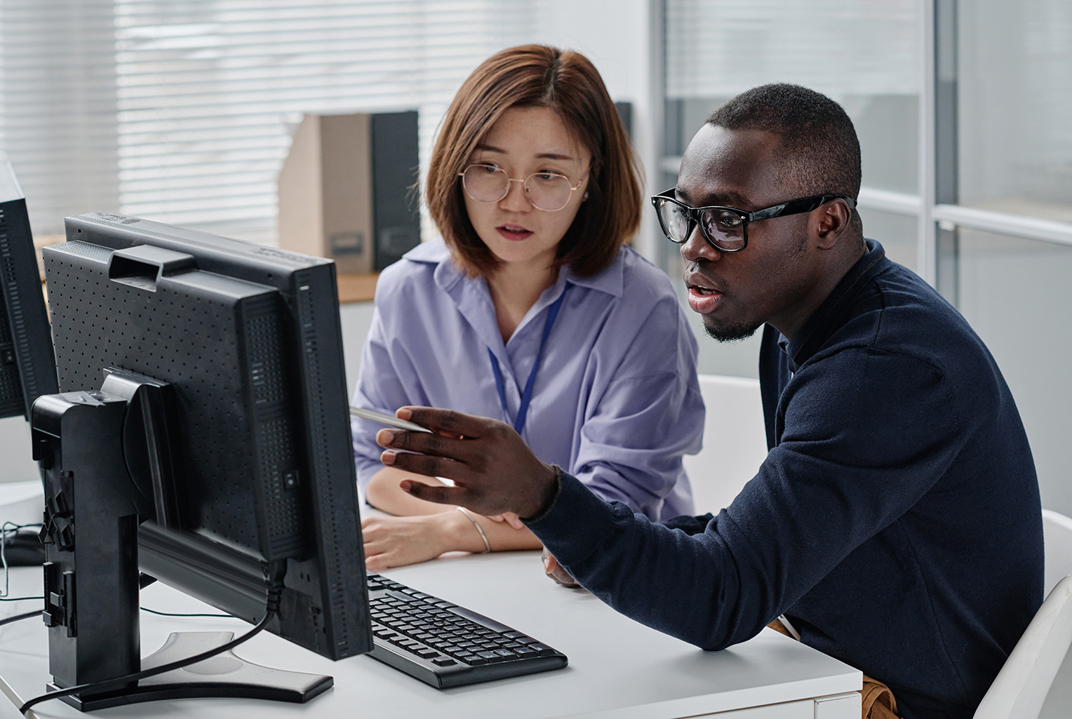 Two colleagues reviewing information on a desktop computer