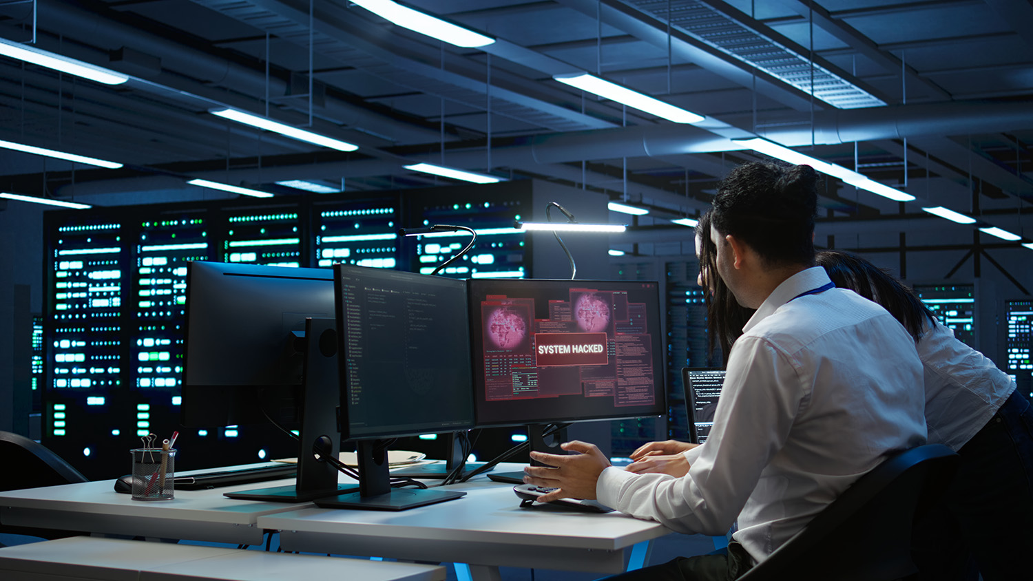 Technician monitoring security screens in a server room