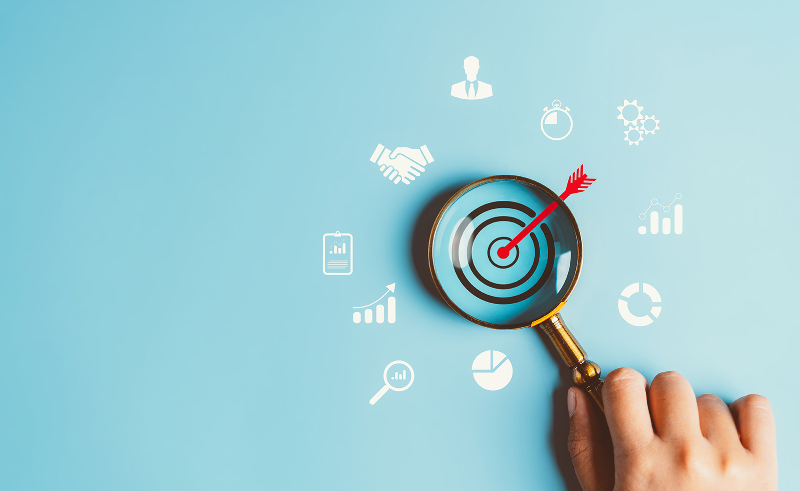 Magnifying glass over a target surrounded by business and analytics symbols