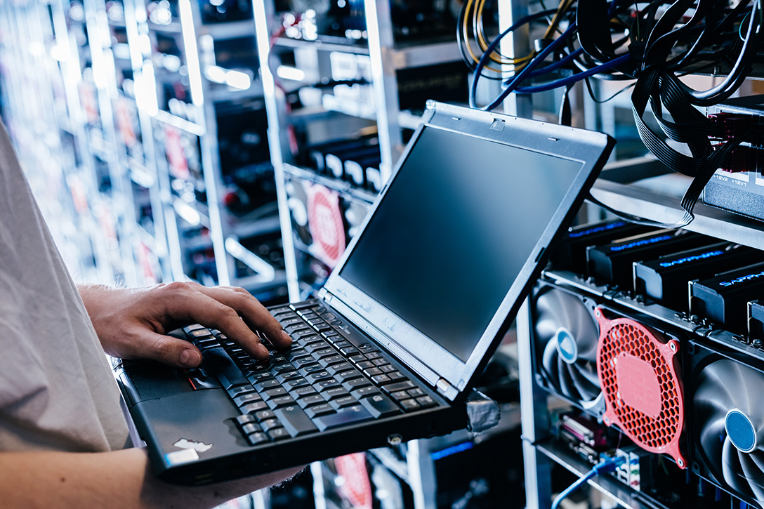 Person using a laptop beside computer equipment