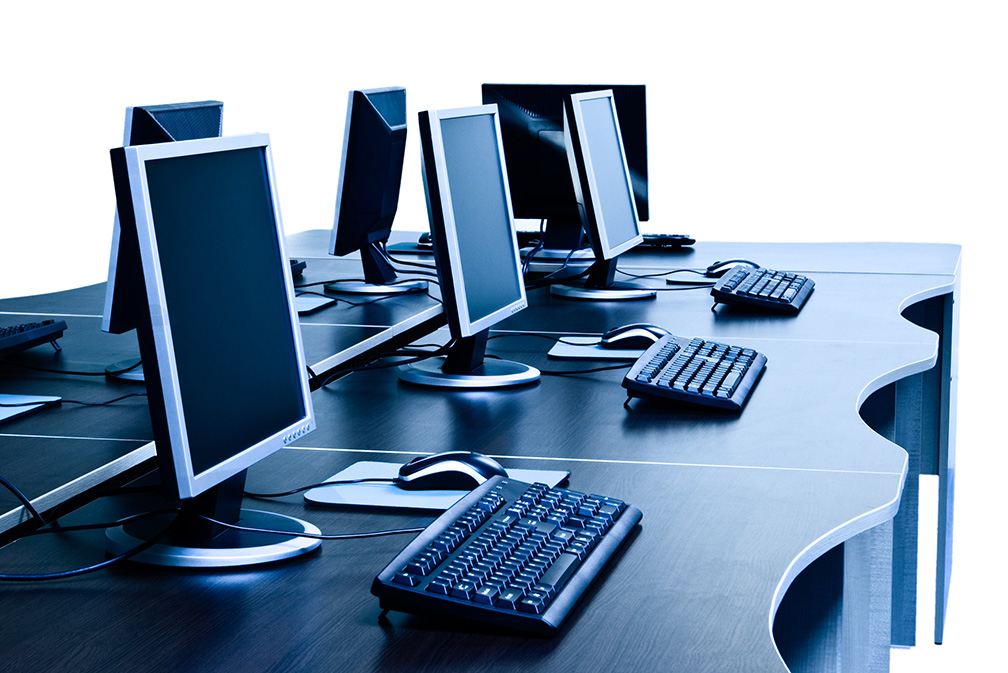 Rows of desktop computers, keyboards and mice in a shared workspace