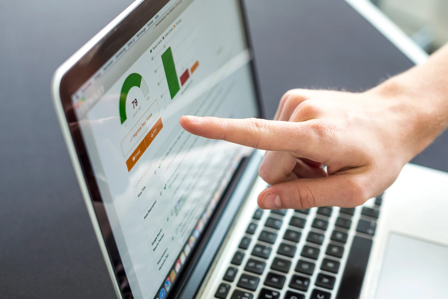 Person pointing to performance charts on a laptop screen